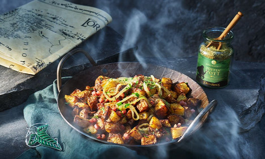 Bratkartoffeln mit Speck und Zwiebeln in Pfanne, daneben Tüften Pott Gewürz in stimmungsvoller Fantasy-Inszenierung.