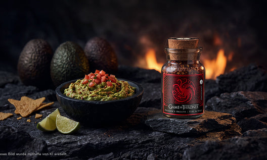 Steinerne Schüssel mit cremiger Guacamole, getoppt mit Tomatenwürfeln, danaben Tortilla Chips sowie Limettenscheiben.