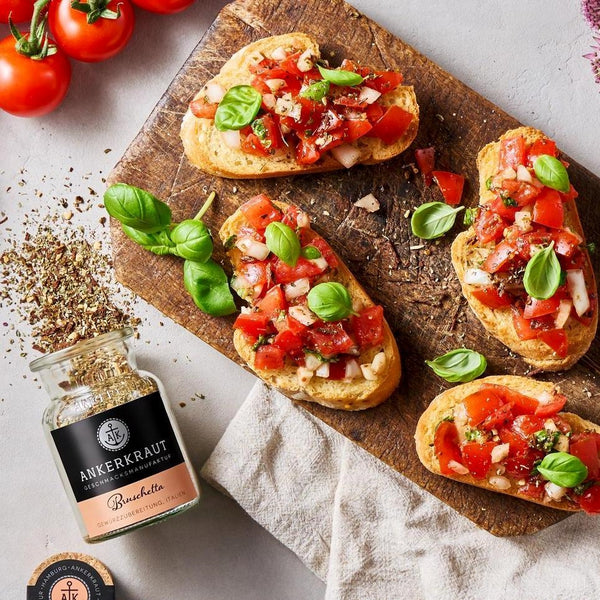 Bruschetta auf einem Holzbrett serviert - dekoriert mit frischem Basilikum.