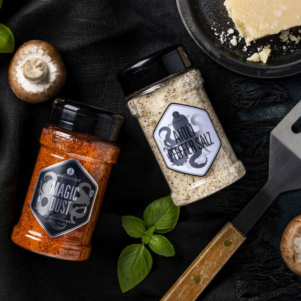 Aioli Gewürzmischung im Gewürzstreuer neben frischen Zutaten und einem Pfannenwender.