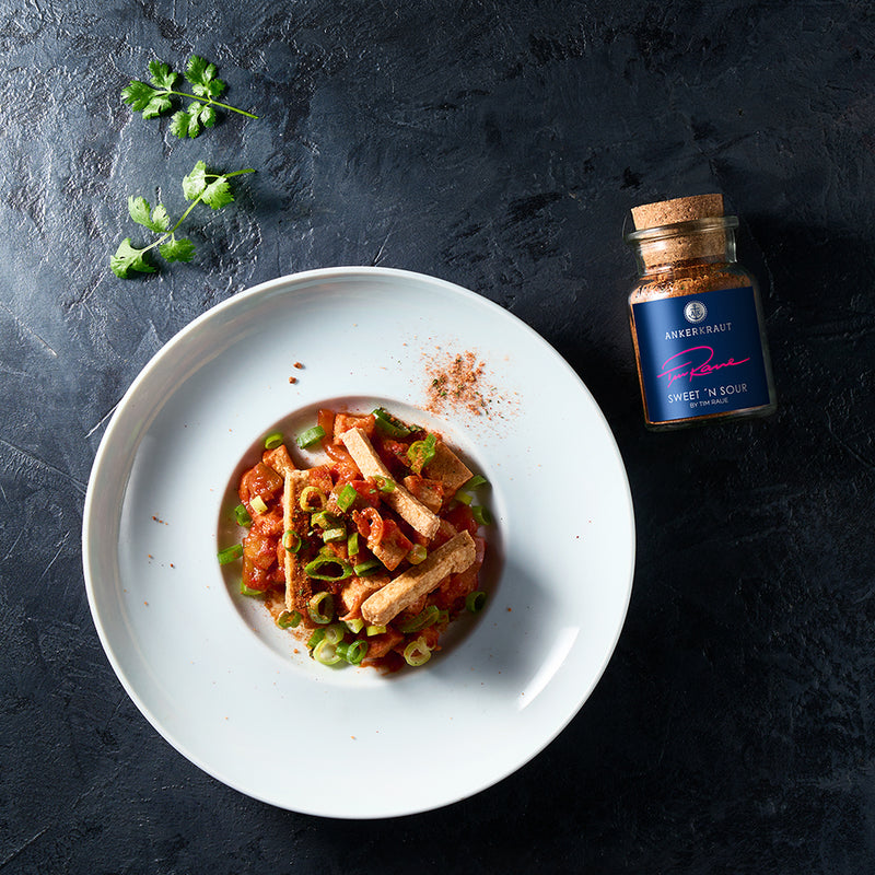 Knuspriger Tofu in Süßsauer-Sauce auf einem weißen Teller angerichtet.